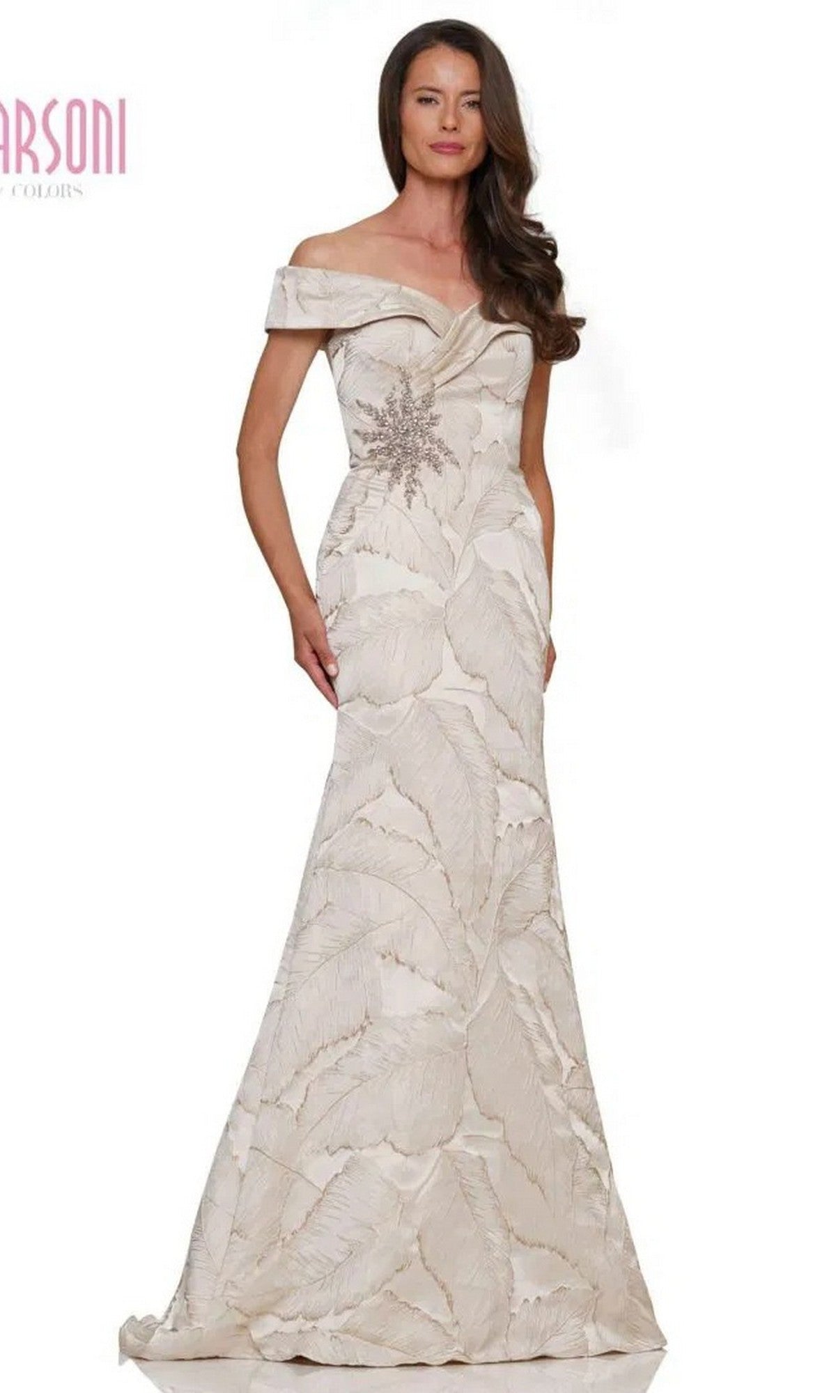 A woman wears the Marsoni MV1266 long formal dress in champagne, an off-the-shoulder evening gown with a leaf pattern and floral embellishments on the bodice, standing against a plain background.
